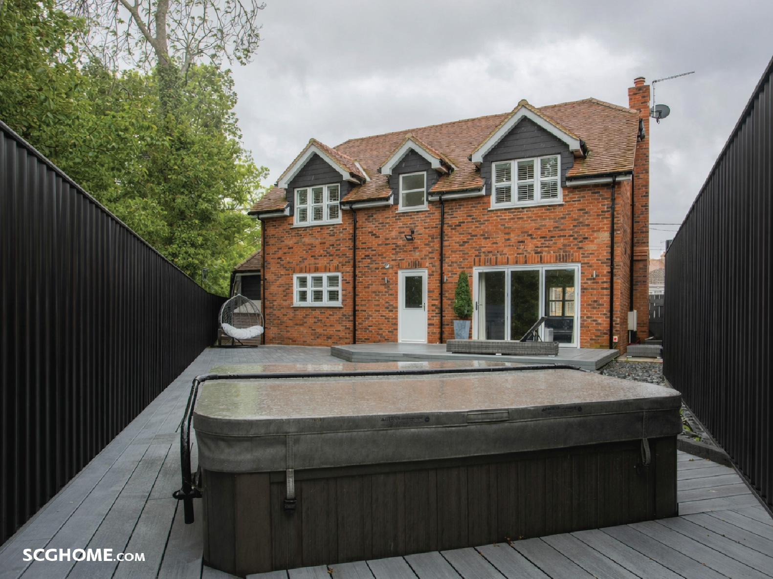 เมทัลชีทสีดำทำเป็นรั้วตัดกับบ้านอิฐสีส้ม