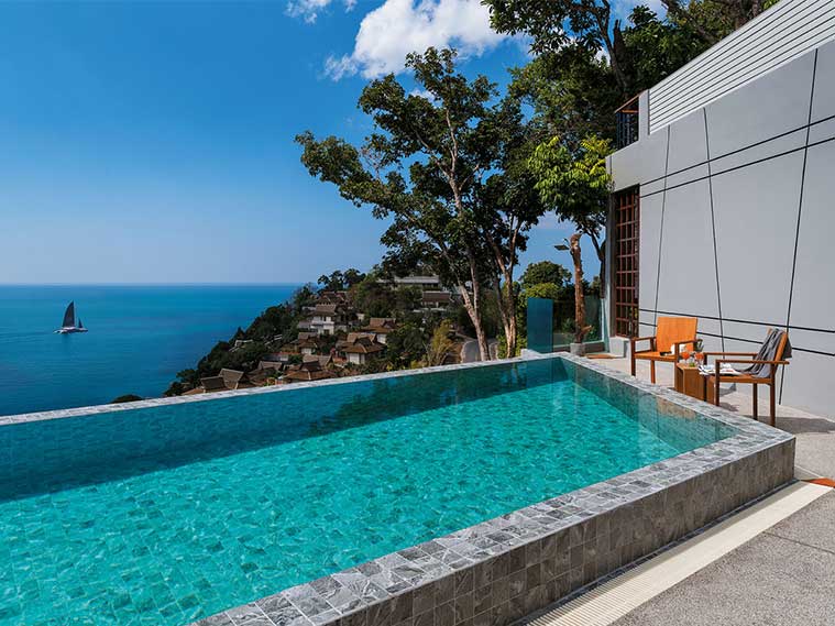 สระว่ายน้ำริมทะเลกับกระเบื้องลายหินเข้มอ่อนสะท้อนผิวน้ำ